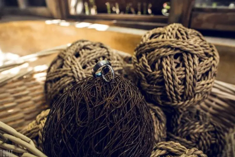 A silver ring rests on top of a dark brown ball of twine, surrounded by tan-colored balls of twine in a woven basket—evoking the thoughtful ambiance of a seminar as sunlight filters in from a nearby window.
