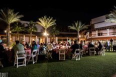 attendees of a corporate event sitting outside at round tables eating