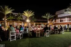 attendees of a corporate event sitting outside at round tables eating