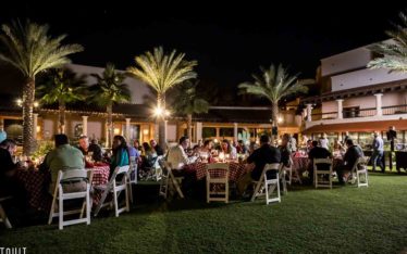 attendees of a corporate event sitting outside at round tables eating