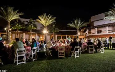 attendees of a corporate event sitting outside at round tables eating