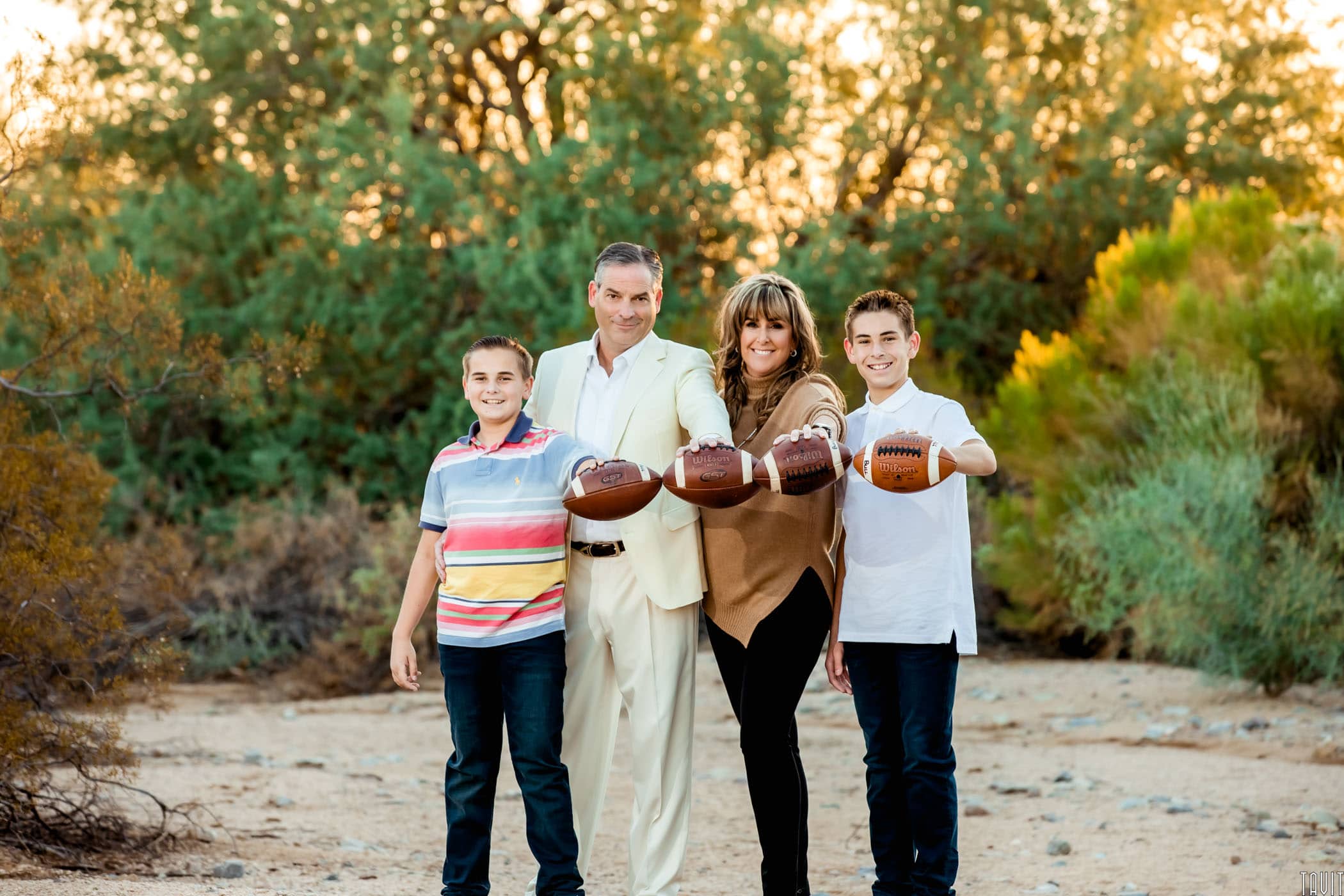 Dad and Mom with their two boys all holding footballs