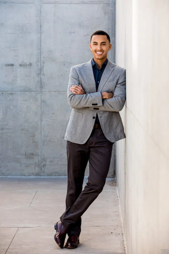 Professional headshot of a man leaning against a wall