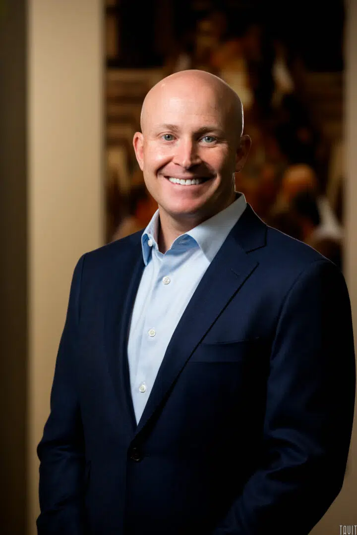 Professional headshot of a man in a blue jacket