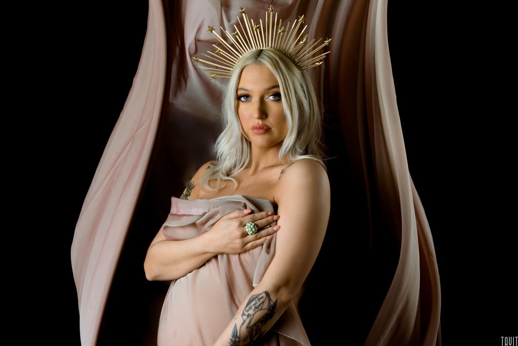 Tattooed woman wearing a crown in a seductive pregnancy shot