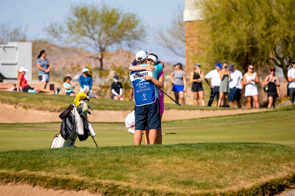 Woman golfer hugging caddie on golf course