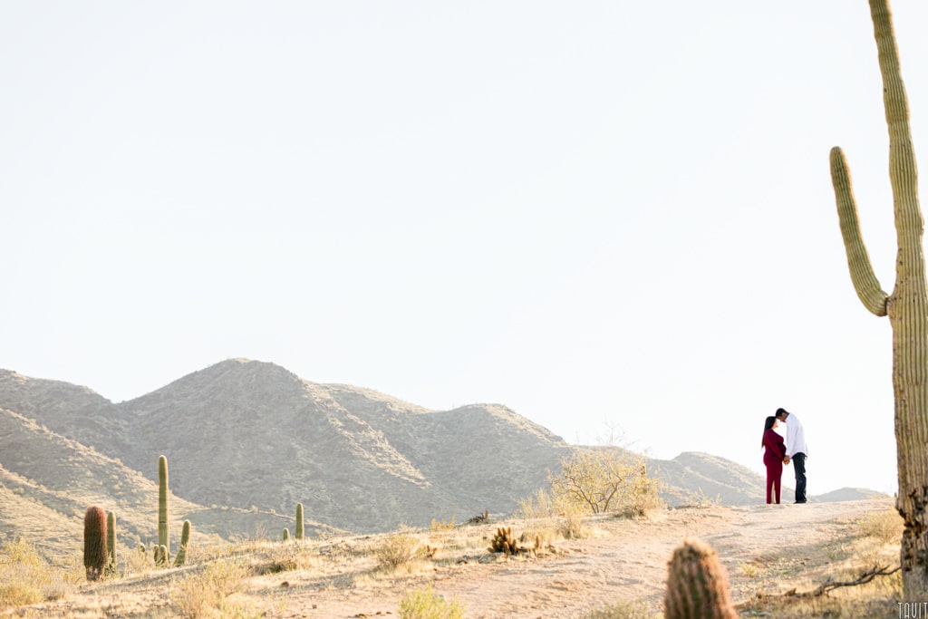 Couple looking at each other in desert for maternity shoot
