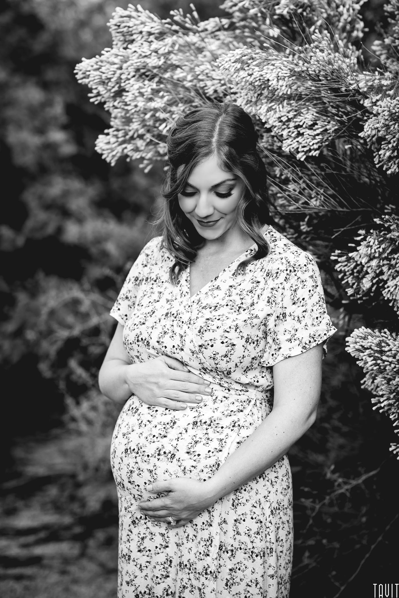 Woman looking down holding tummy for maternity shoot black and white