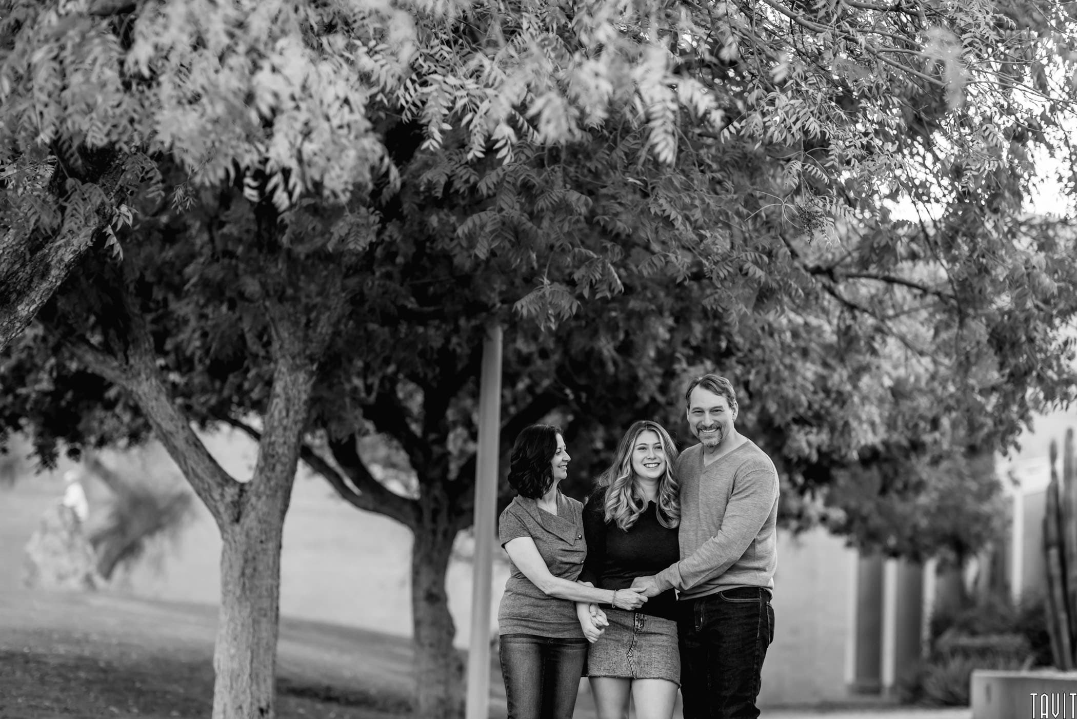 Family standing under tree smiling black and white