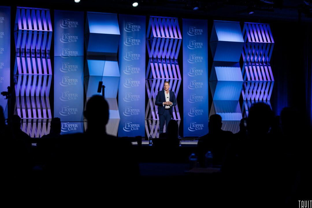 Man giving speech on stage for Topper Club