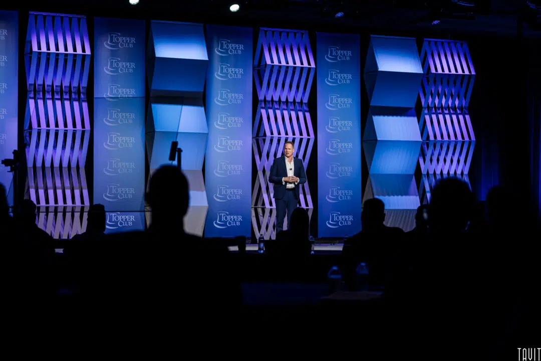 Man giving speech on stage for Topper Club