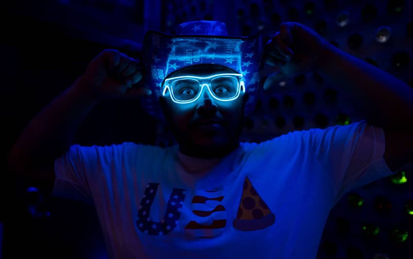 Man in glow glasses with arms up