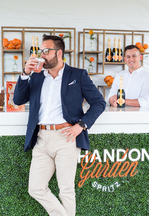 Man drinking cocktail in front of garden bar
