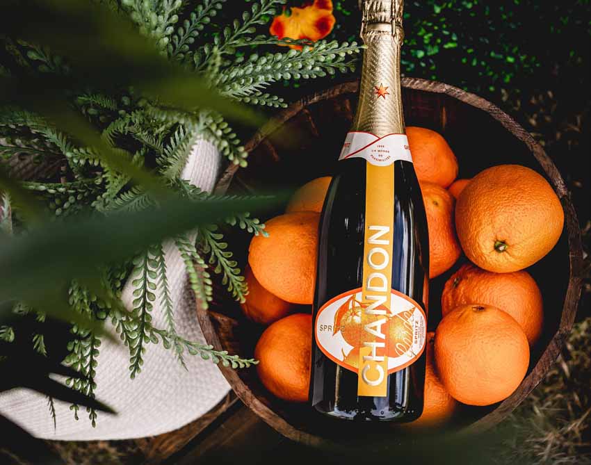 Bottle of Chandon champagne on top of a barrel of oranges