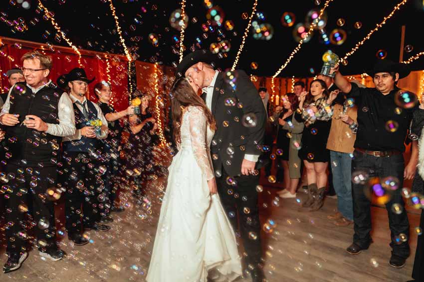 Bride and groom kissing surrounded by bubbles