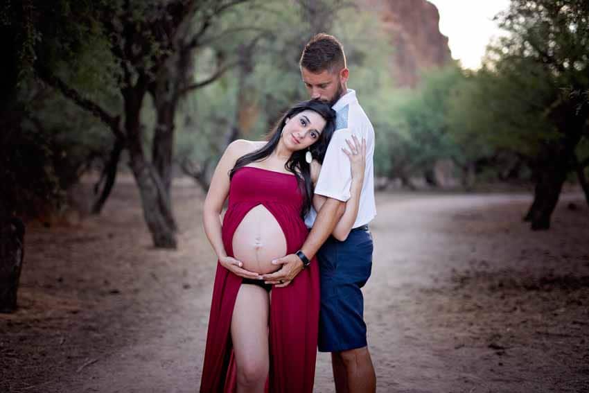 Couple holding pregnant woman's tummy in desert