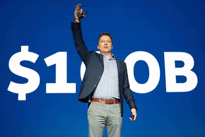 Man with arm raised in front of $100B sign