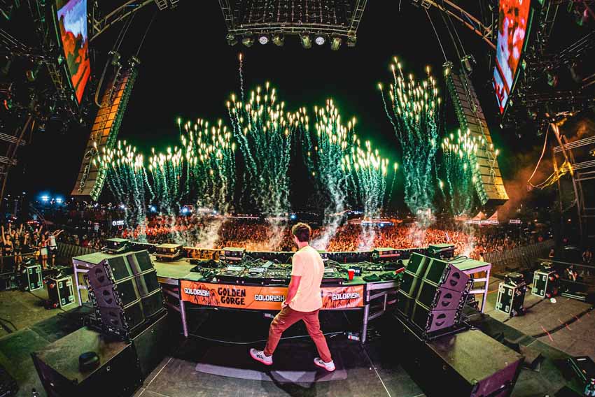 DJ on stage in front of crowd with fireworks