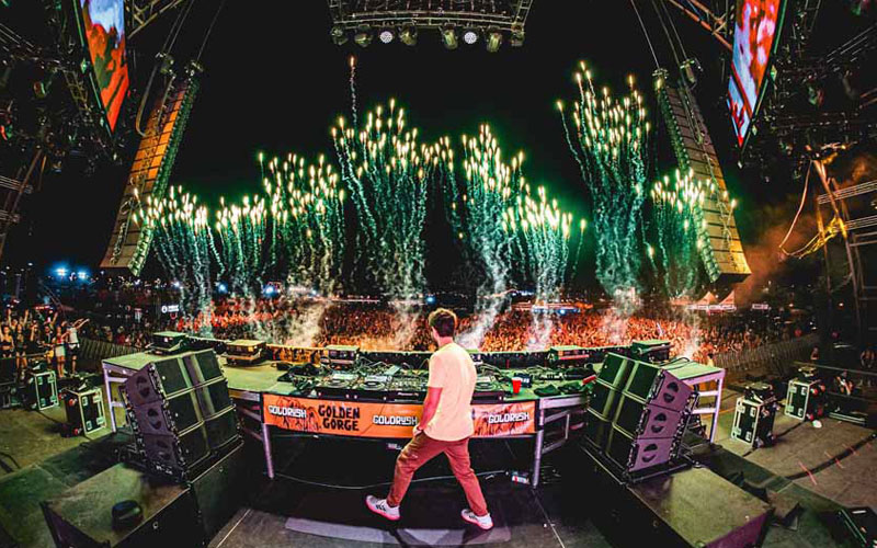 DJ on stage in front of crowd with fireworks