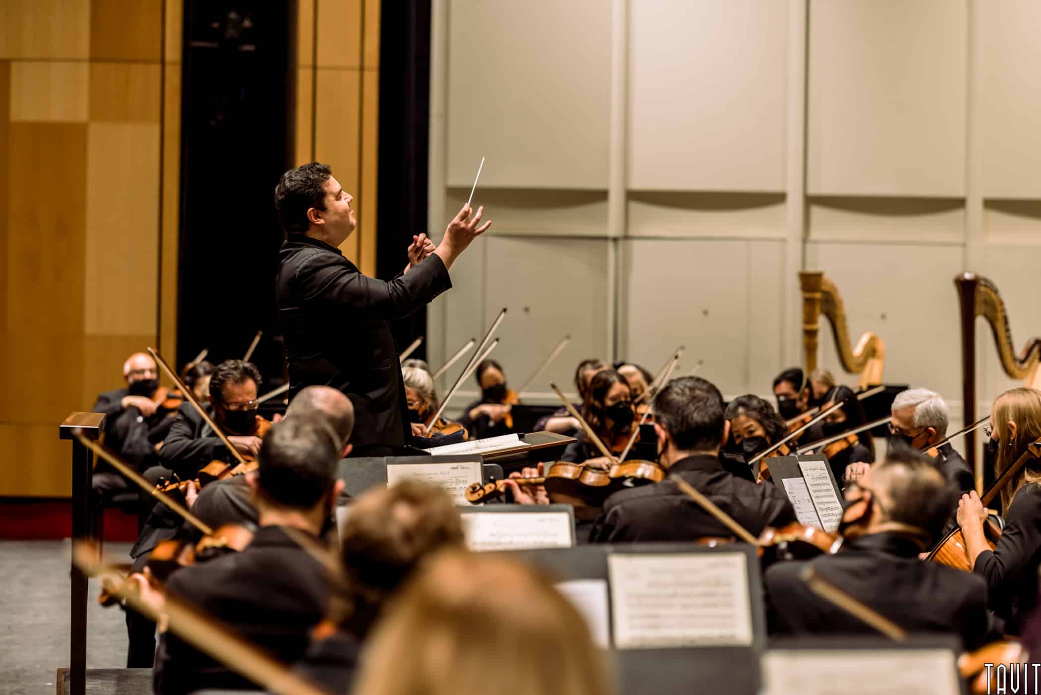 Side view of conductor with arms out in front of orchestra