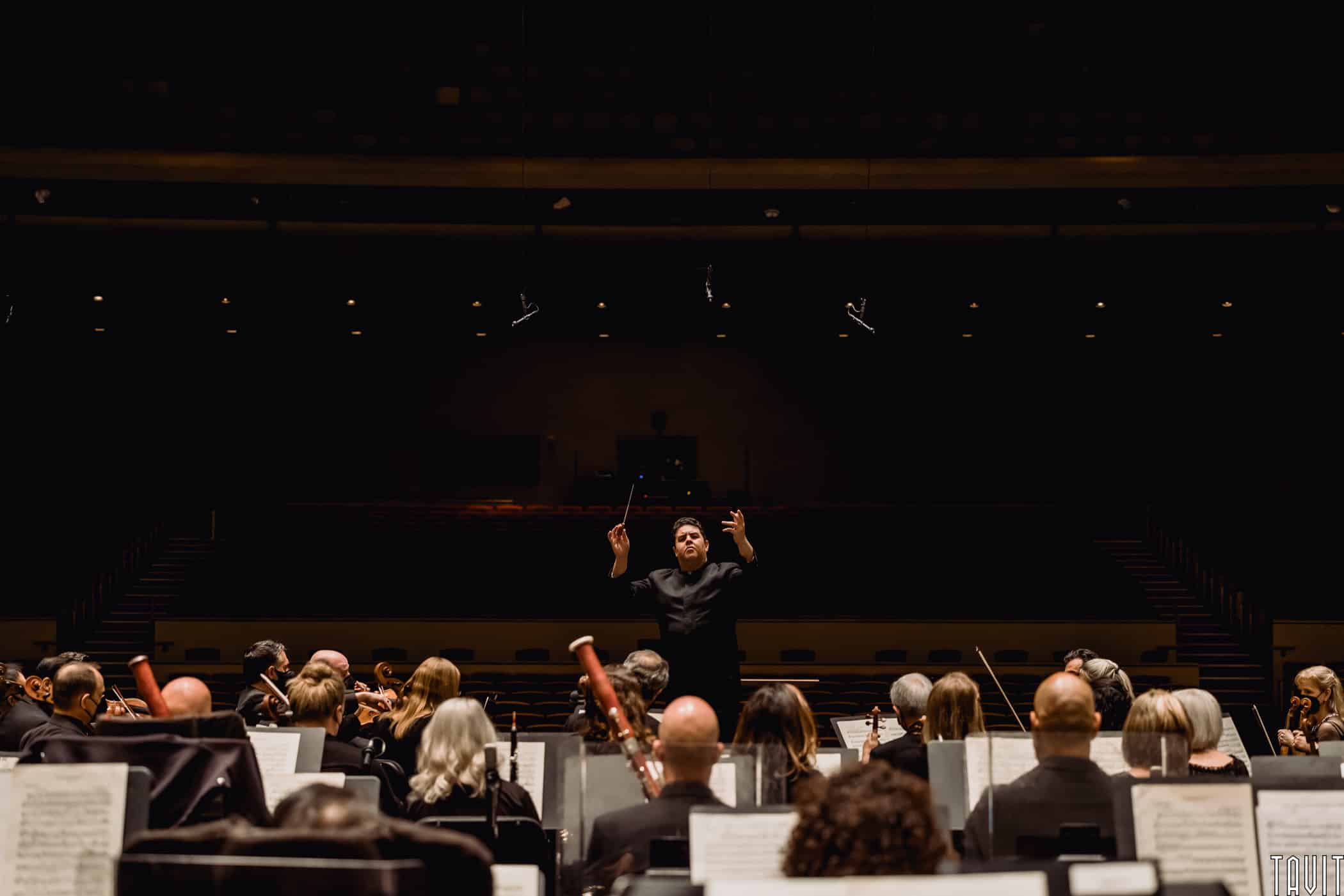 Conductor with arms out in front of orchestra