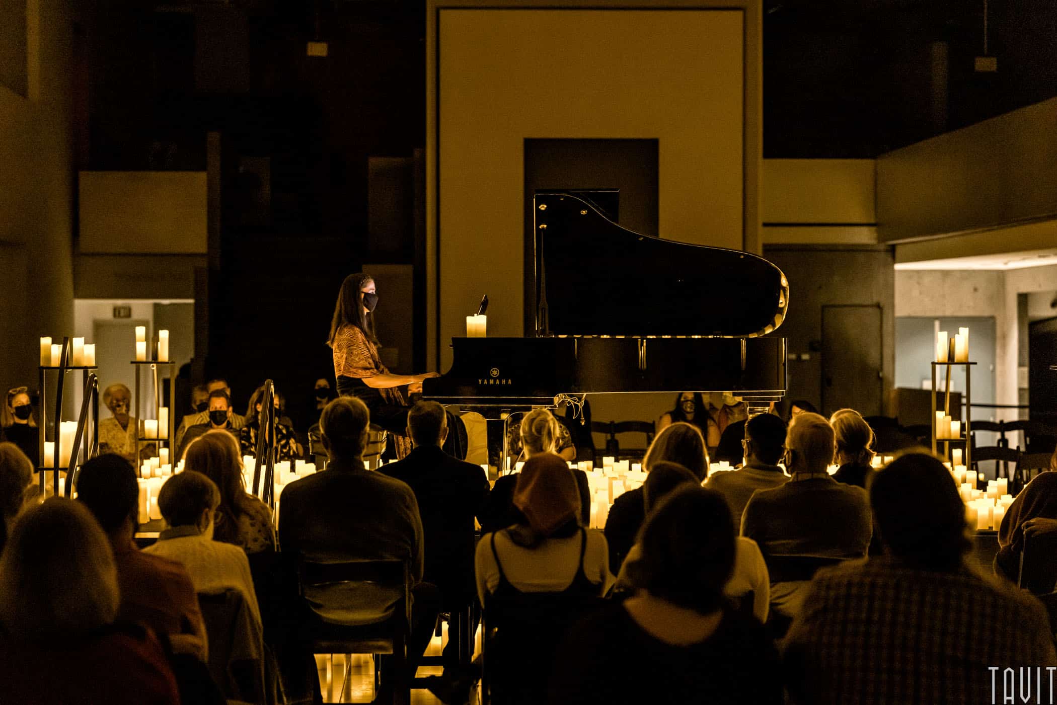 Pianist playing on stage with candles and audience