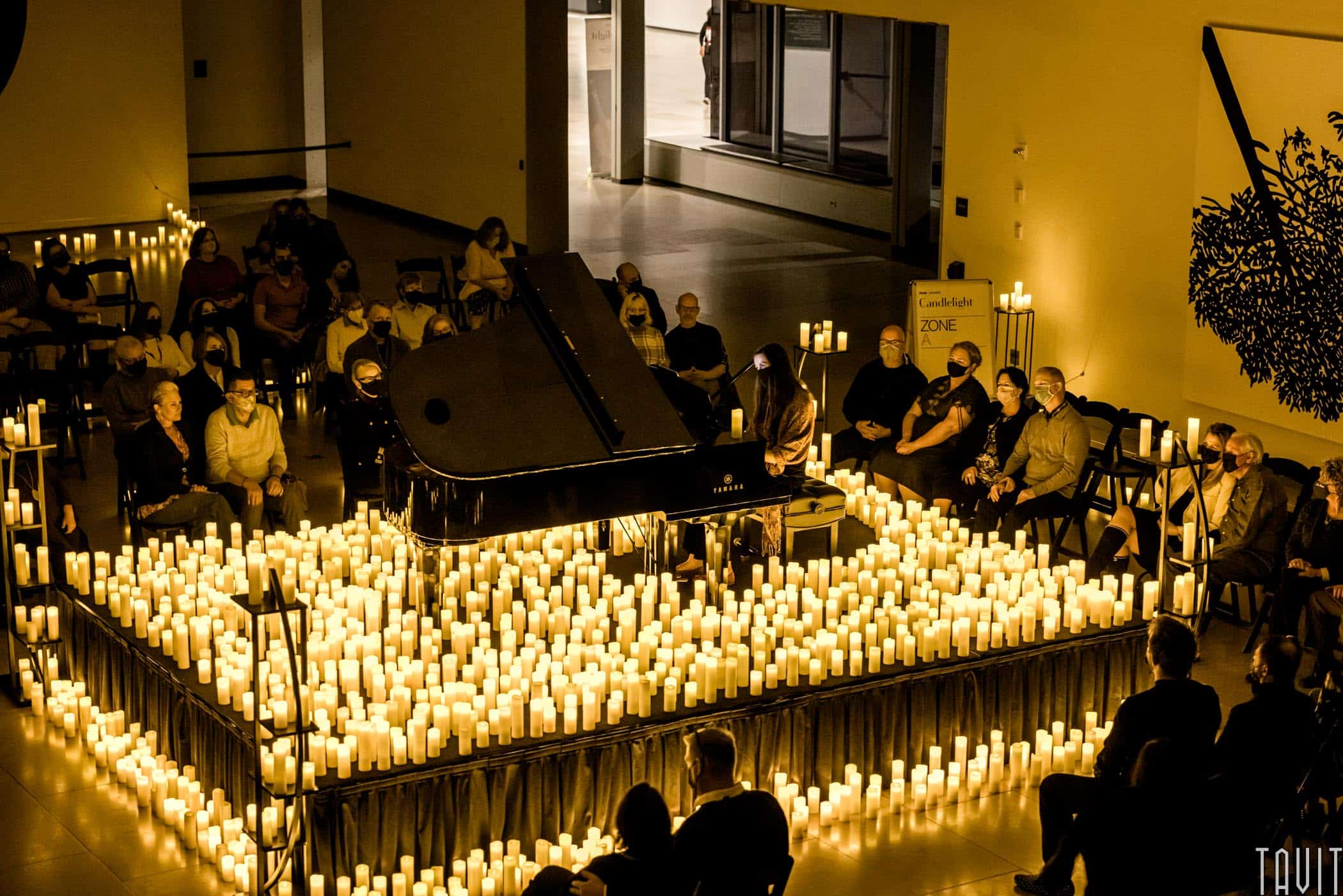 Pianist playing on stage surrounded by candles and audience