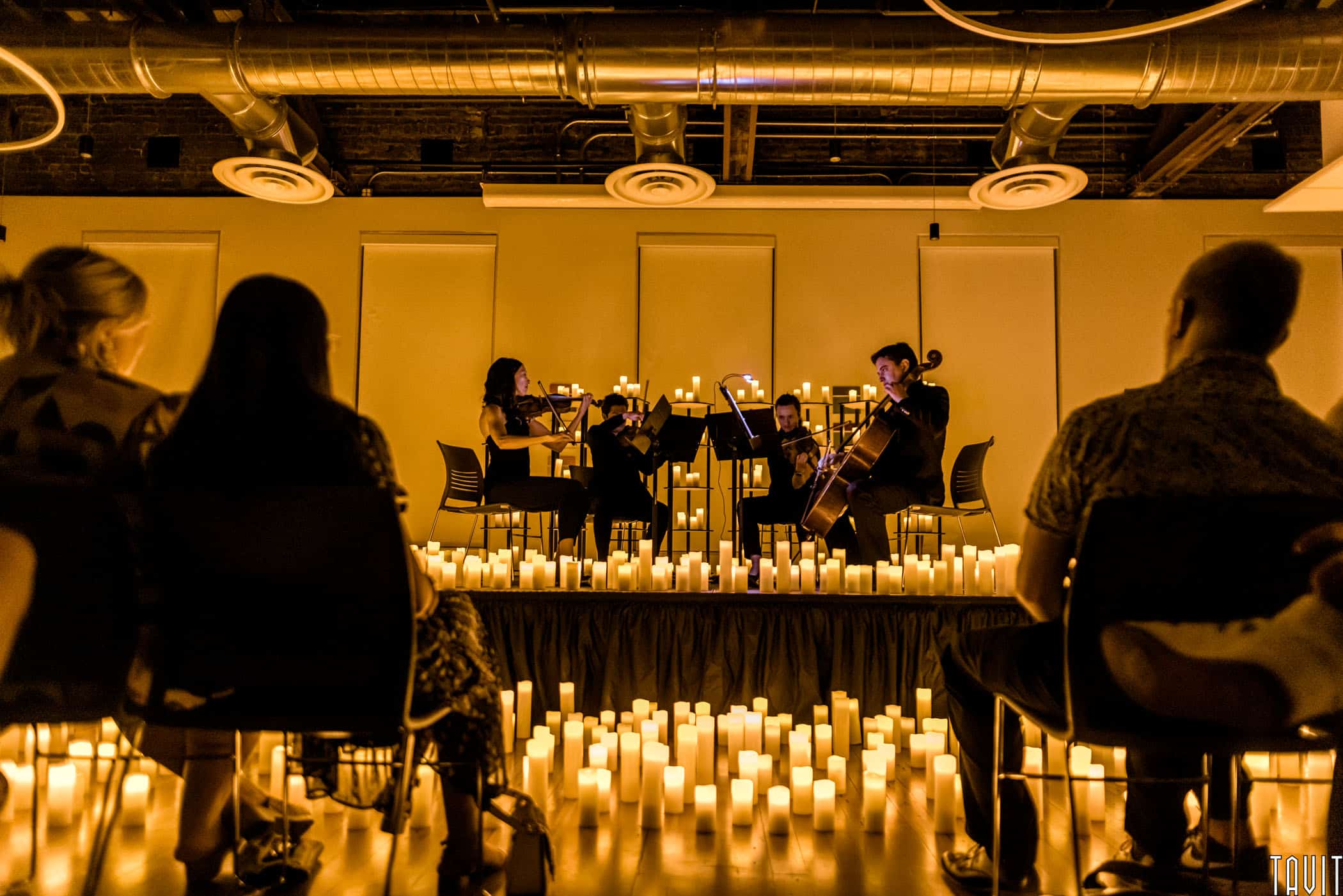 String quartet playing on stage surrounded by candles