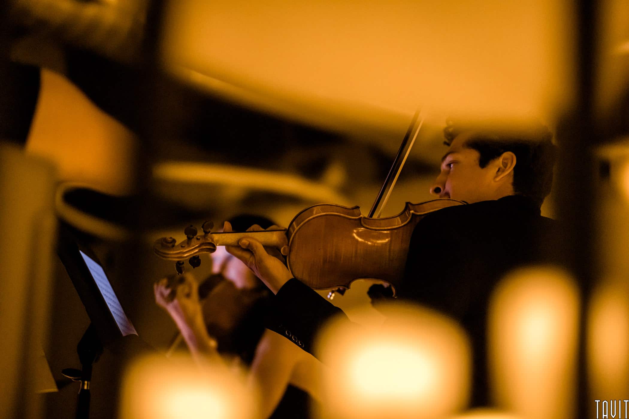 Violinist playing surrounded by candles