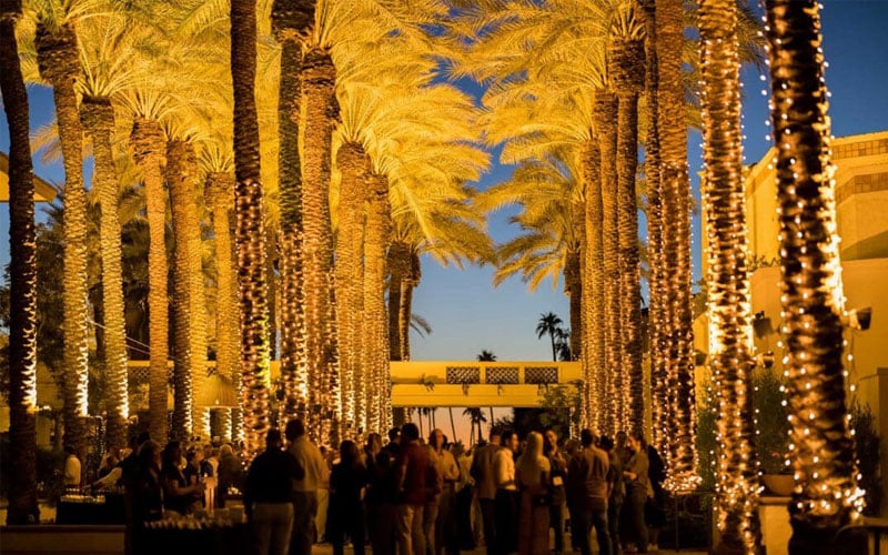 Corridor with lit palm trees and crowd