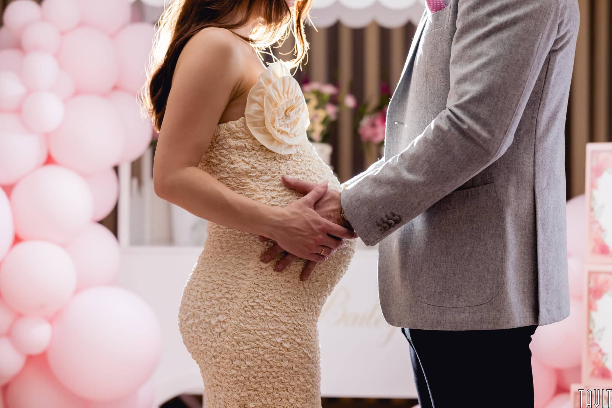 Man holding woman's pregnant tummy at baby shower