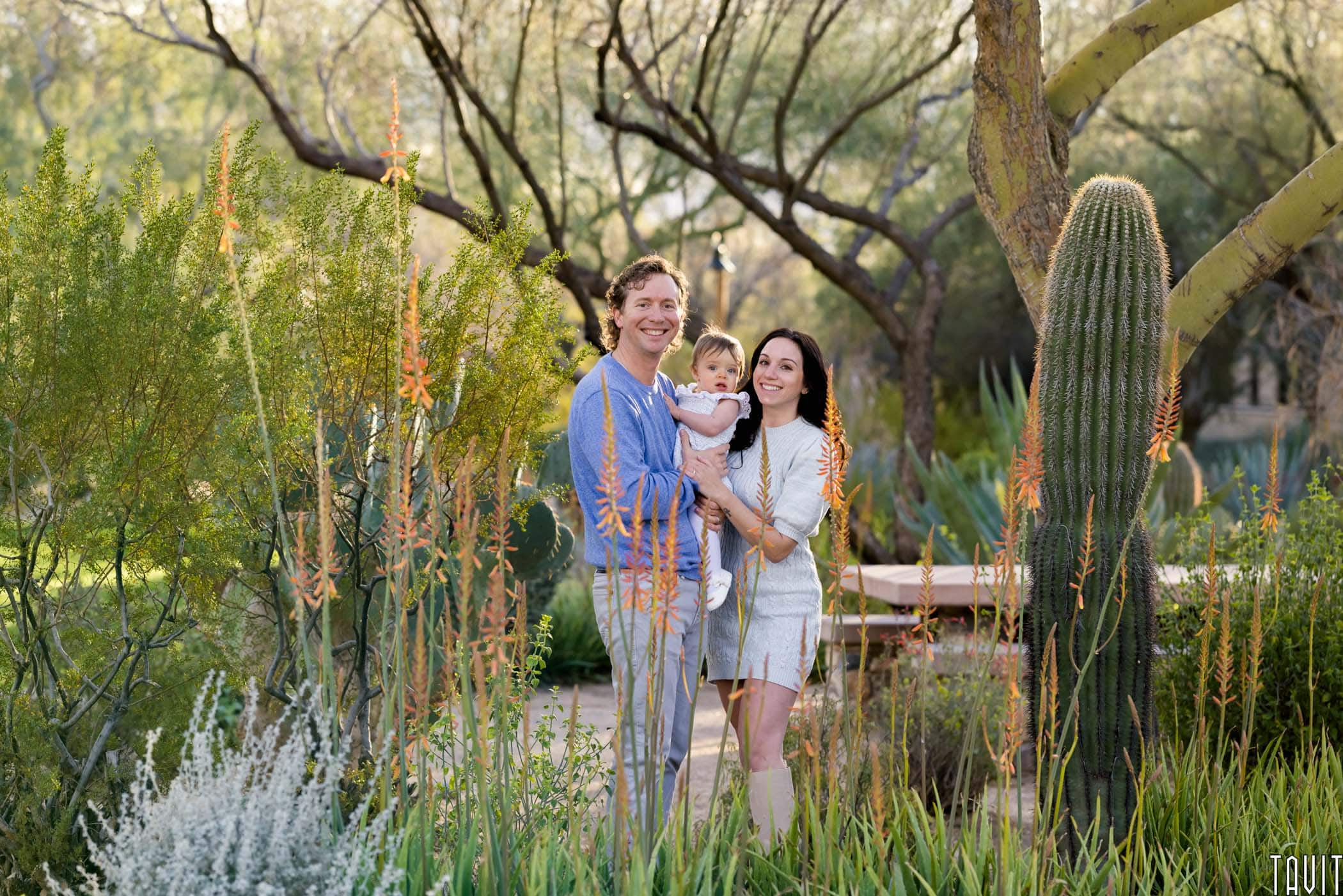 Couple smiling while holding baby near desert plants