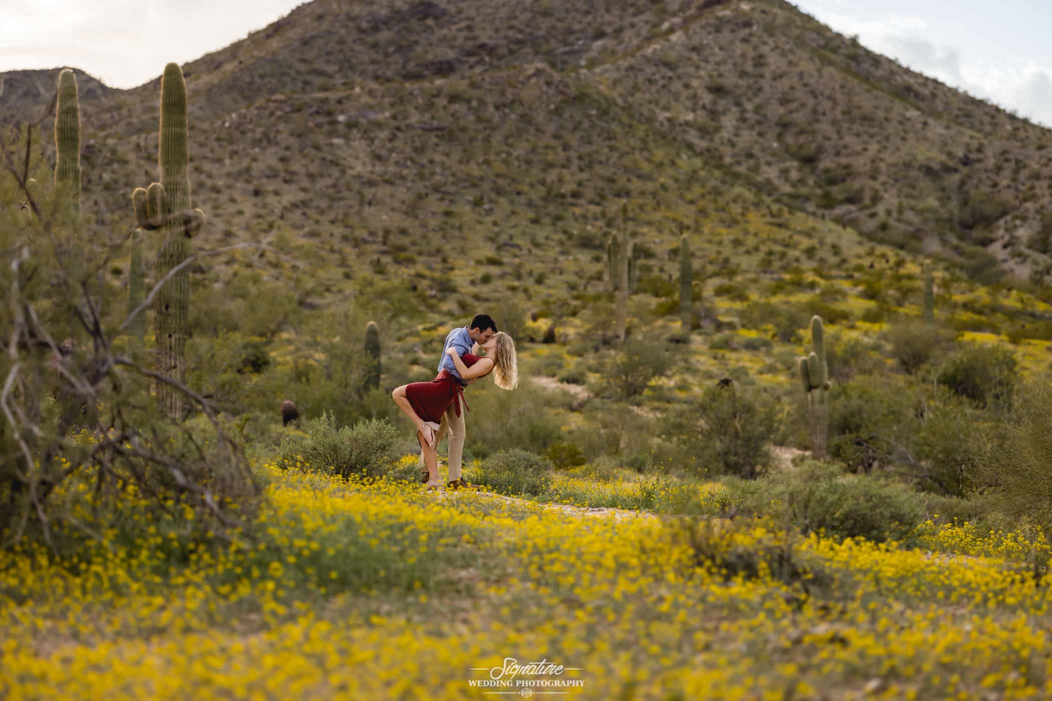 Man dipping woman and kissing in front of desert mountain