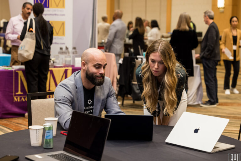 man and woman at a conference looking at a laptop screen