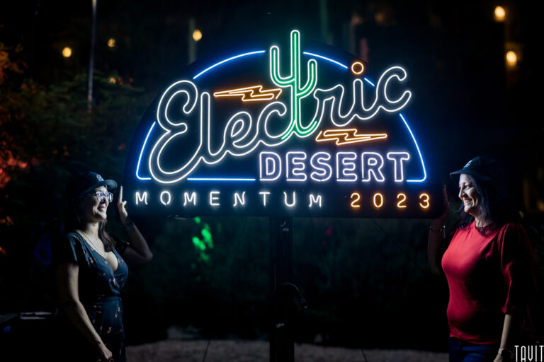 two women in front of neon Electric Desert sign at Momentum 2023 event