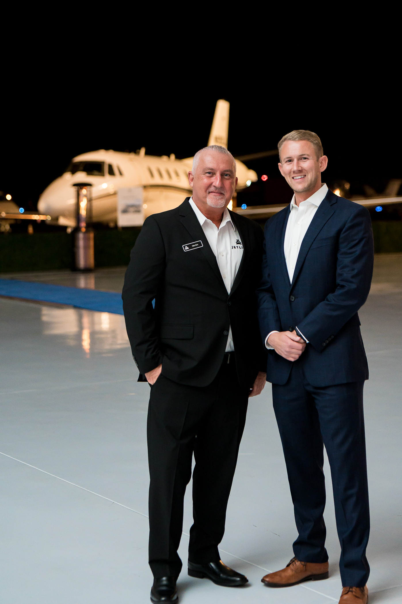 Two men smiling in front of private jet