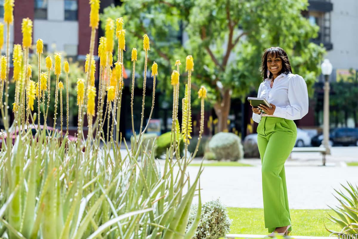 professional business shot of woman standing outside next to plants