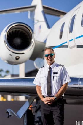 Professional headshot of pilot with jet in the background