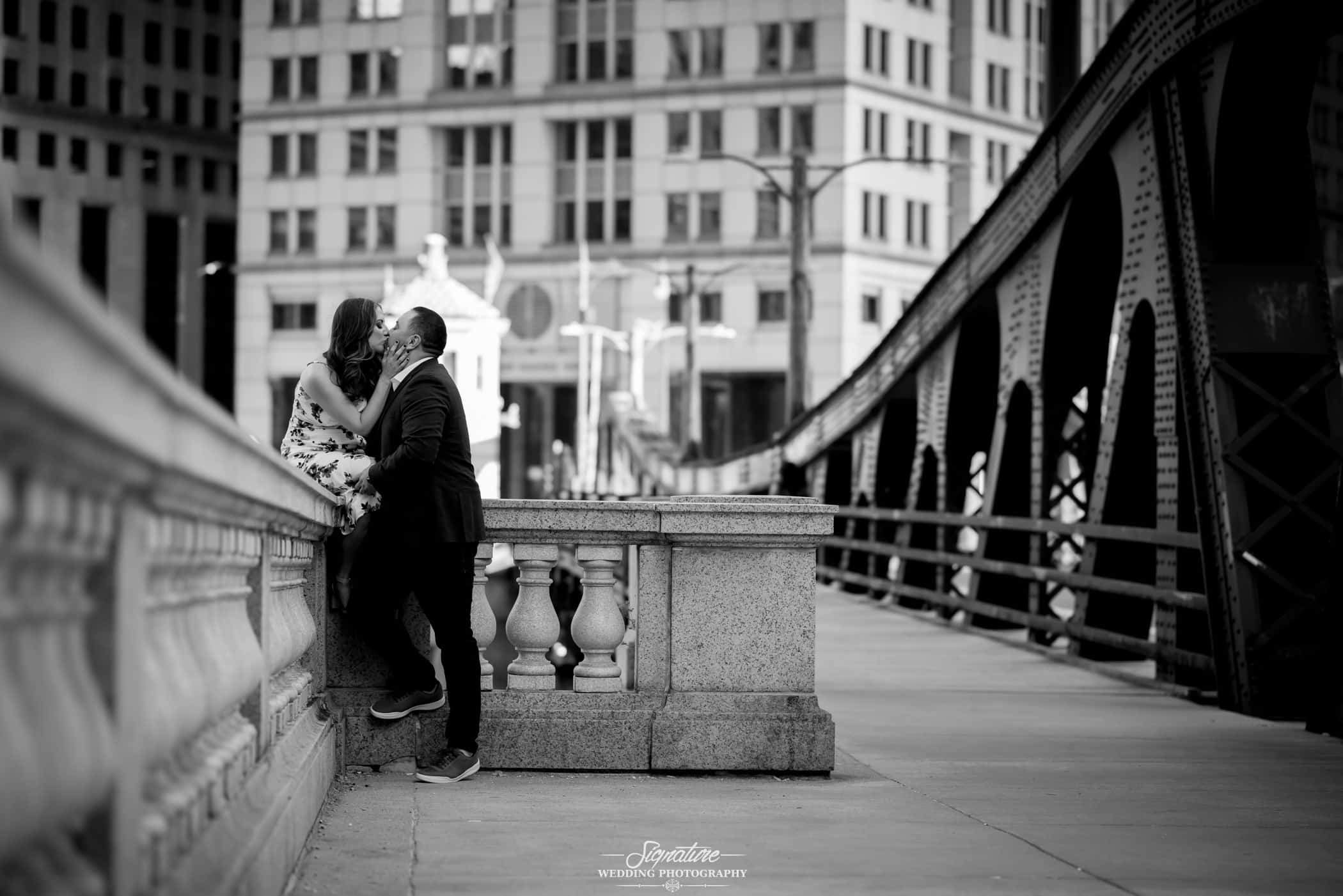 Couple kissing sitting on bridge black and white