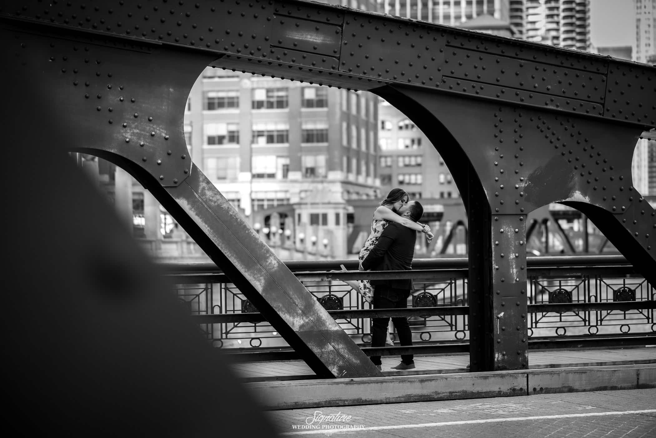 Man picking up woman and kissing on bridge black and white