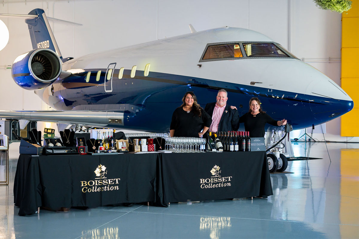 People at display table in front of plane