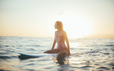 girl on surfboard in Hawaii at sunrise