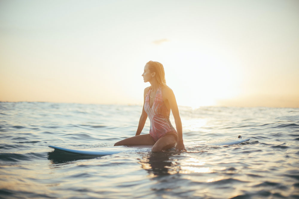 girl on surfboard in Hawaii at sunrise