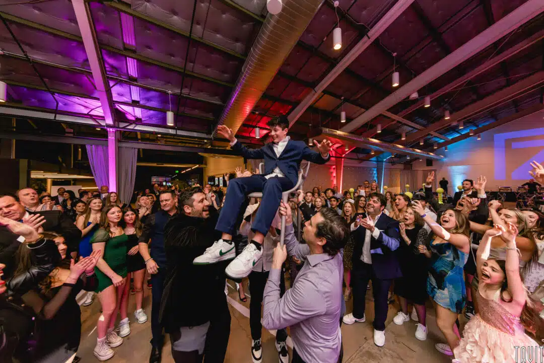 a young man at his Bar Mitzvah being held up in a chair by other men