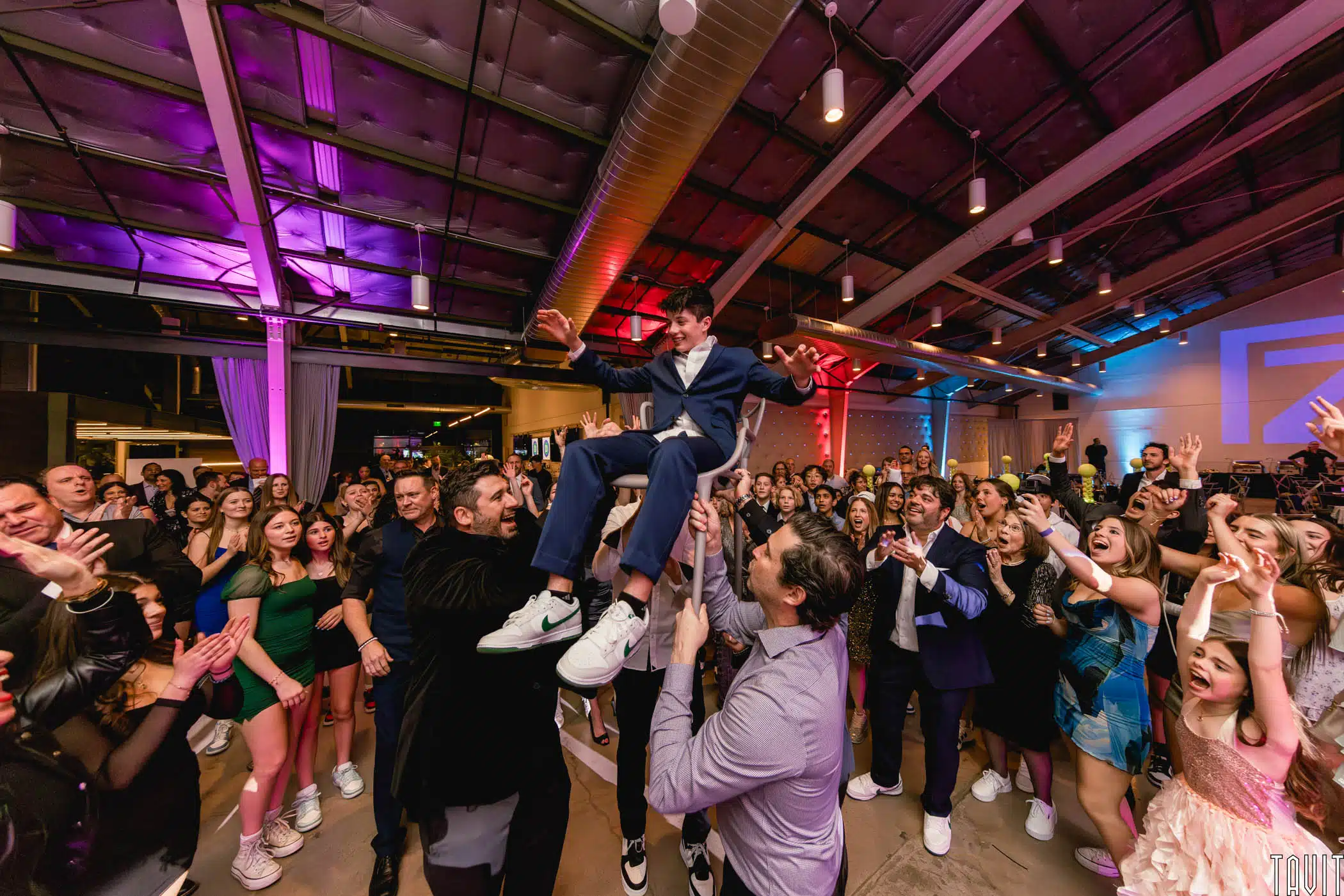 a young man at his Bar Mitzvah being held up in a chair by other men