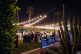 Corporate event in the evening with people gathered under string lights, surrounded by palm trees and cacti