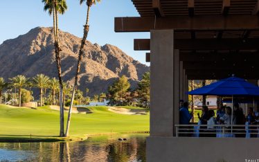 Professional outdoor corporate networking event at a luxury desert resort in Palm Springs featuring a modern patio, high tables, and palm trees against a dramatic mountain backdrop at sunset.